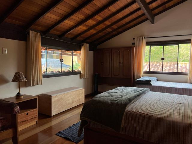 Room with double and single beds under a wooden ceiling
